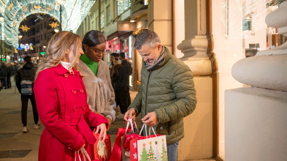 group of holiday shoppers mixed races ages and genders in retail shopping mall wearing cold weather attire carrying holiday purchases