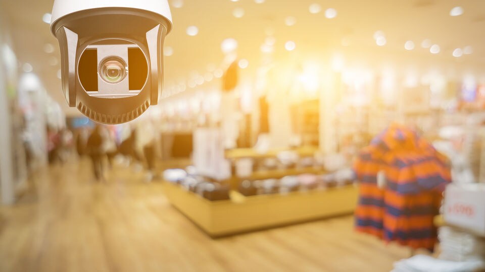 video surveillance camera on ceiling of retail clothing store with gold colored filter over image