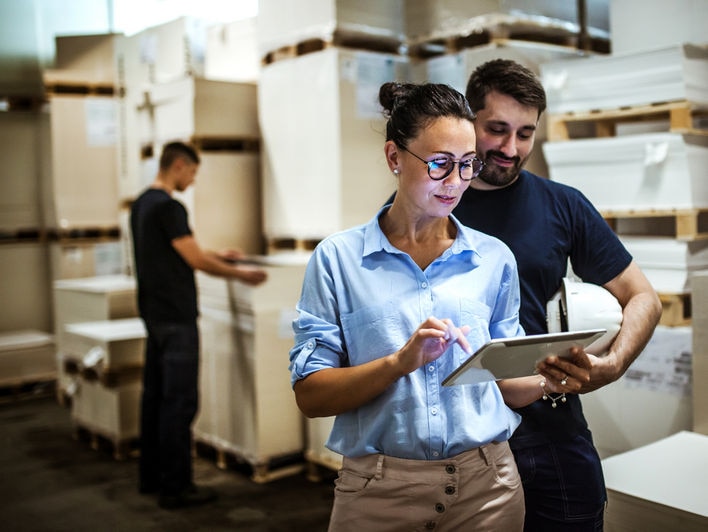 Travailleurs en entrepôt accédant aux données analytiques en magasin via un appareil mobile