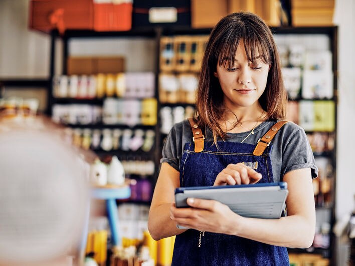 Un employé d’un magasin consulte les rapports d’inventaire sur un appareil mobile